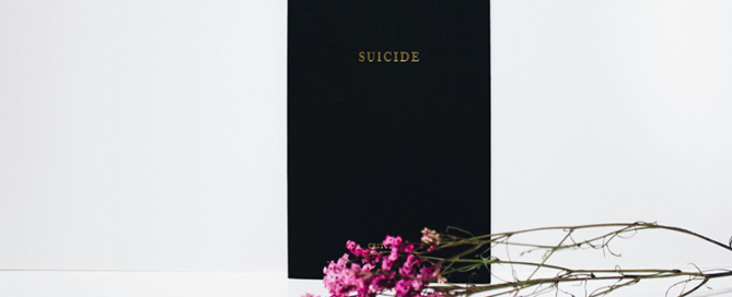 A compassionate hand holding a phone displaying key mental health helpline numbers Suicide Crisis Helpline and Kids Help Phone.